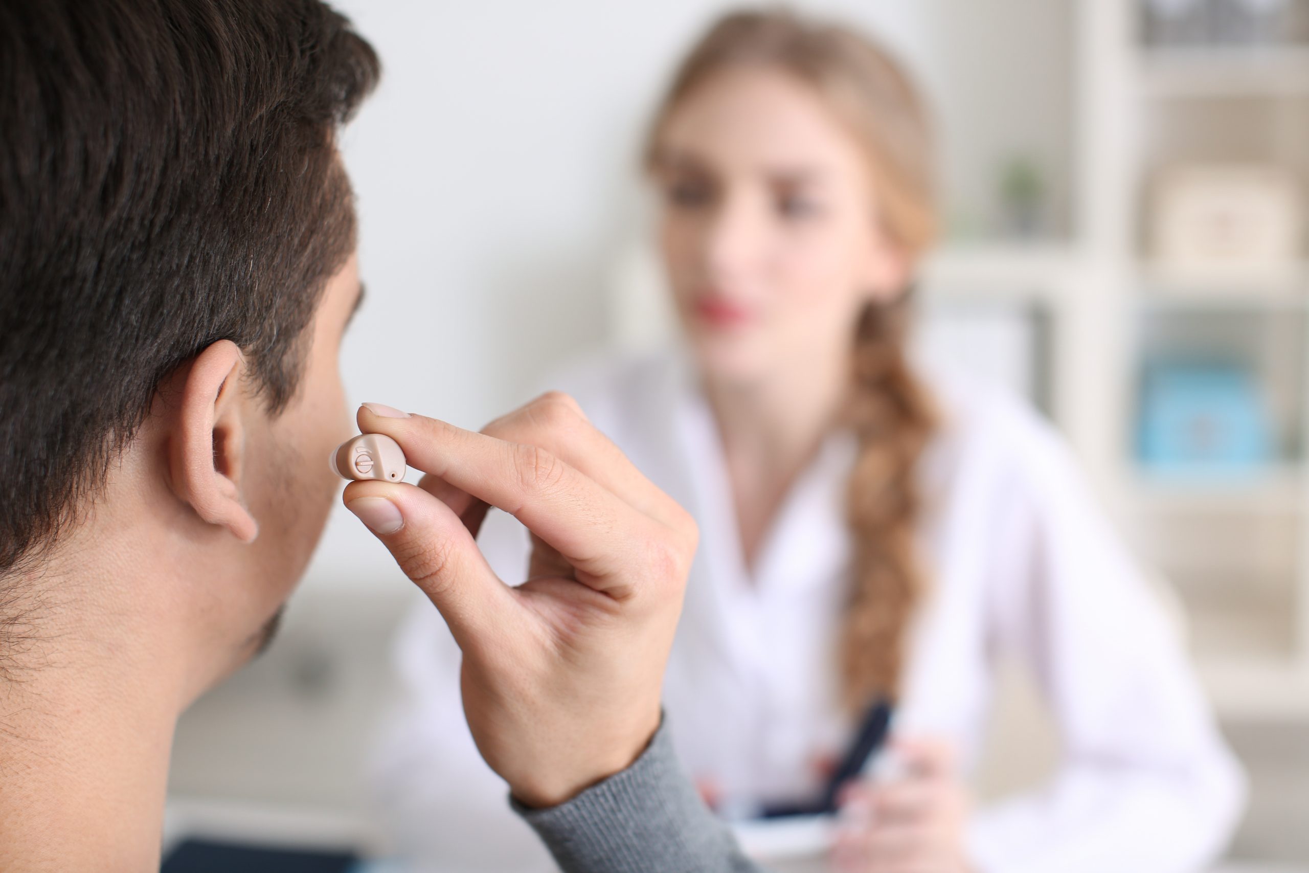 Man putting on hearing aid in doctor’s office