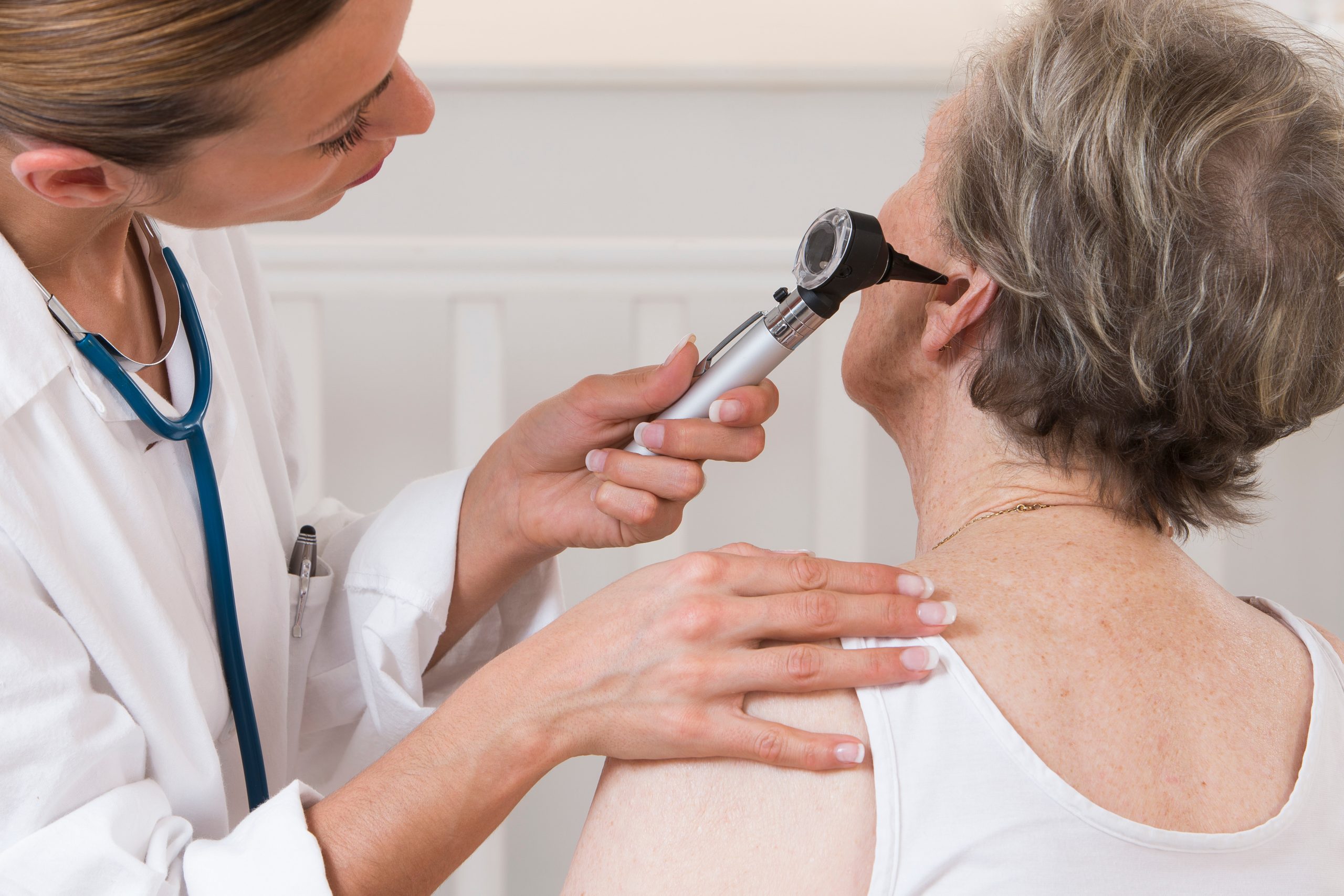 doctor examining elderly patient’s ears