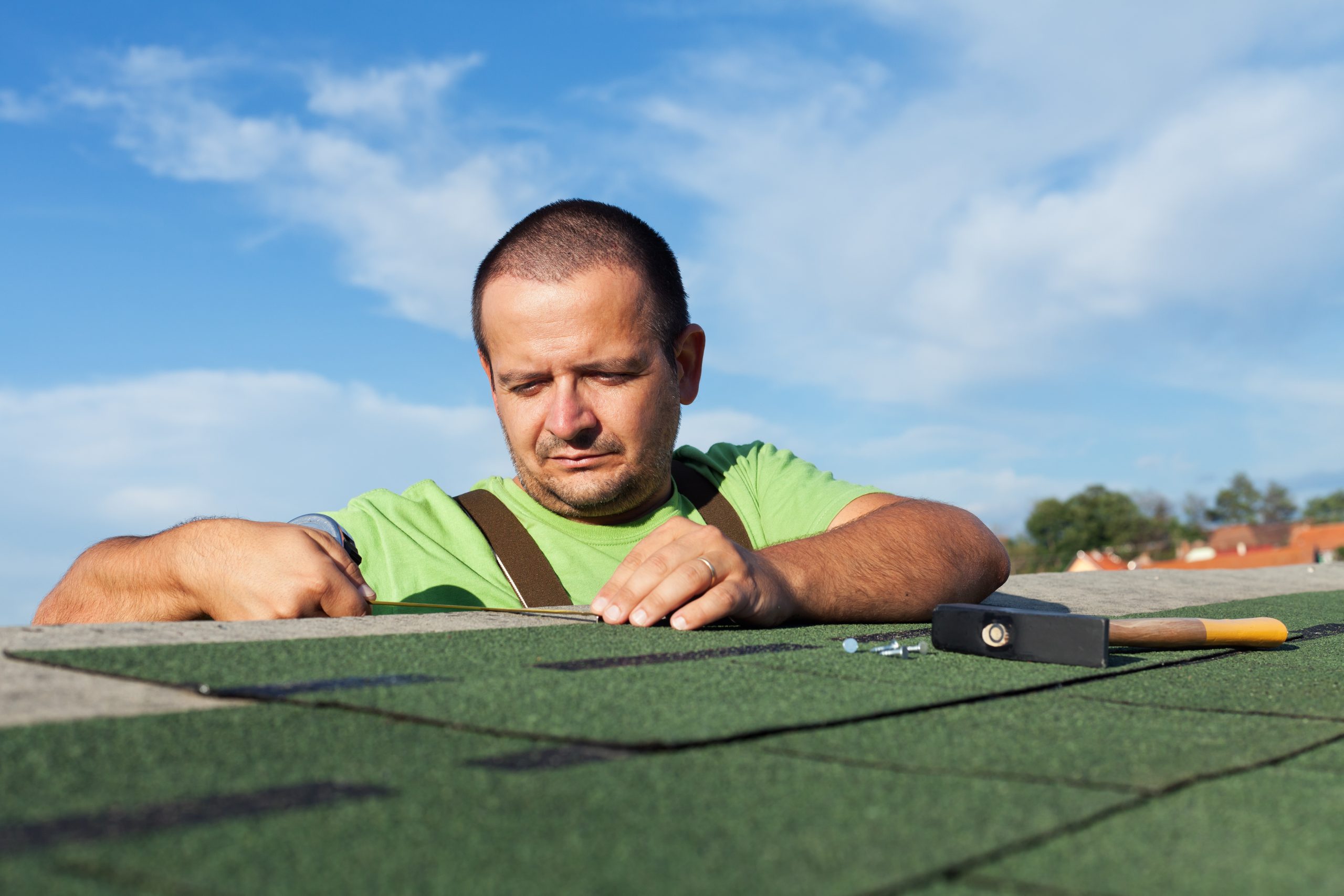 Installing the last strip of bitumen roof shingles